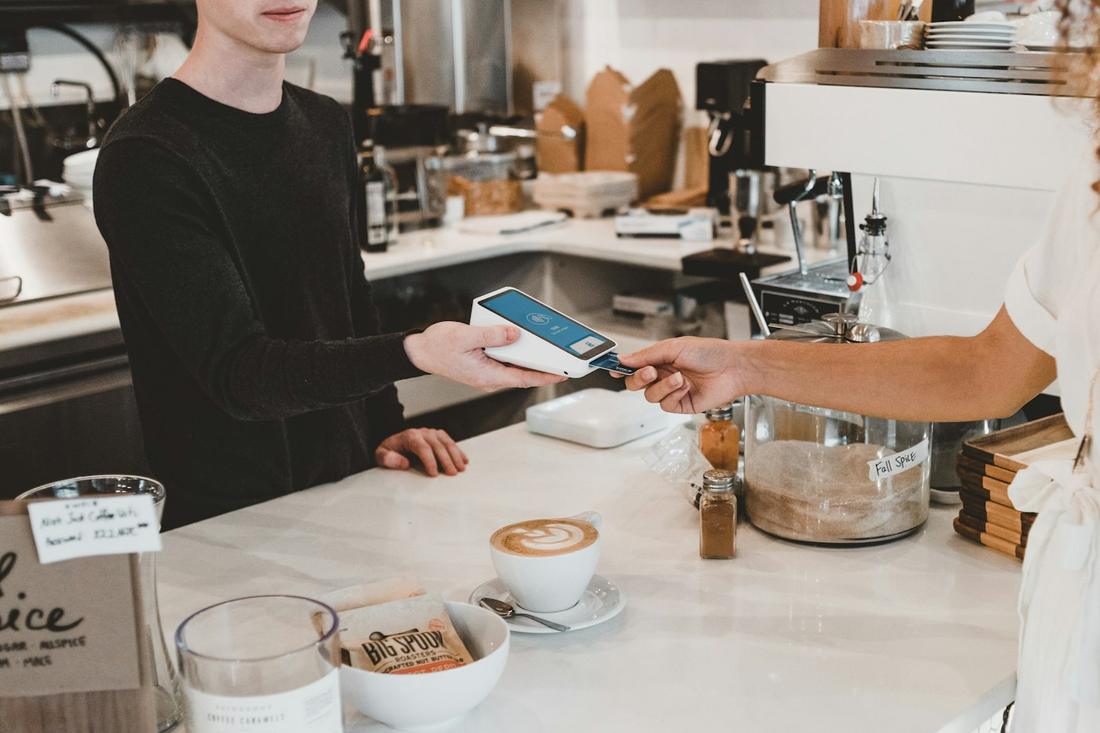 A card tapped on a Square reader across a coffee counter