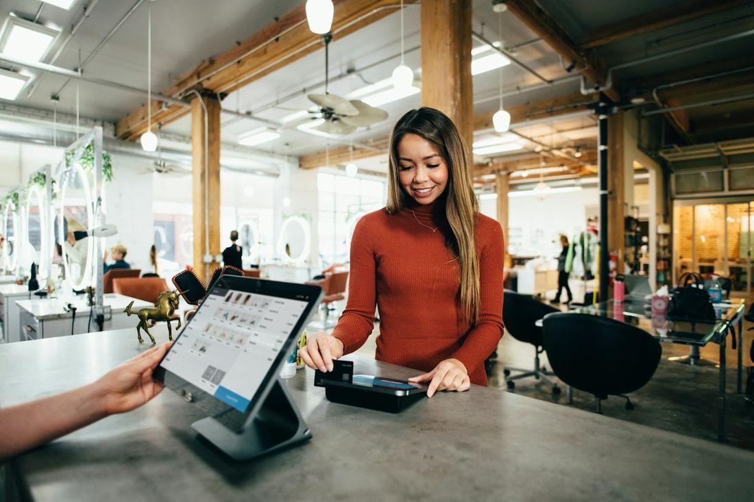 A customer paying at a salon front desk running Square